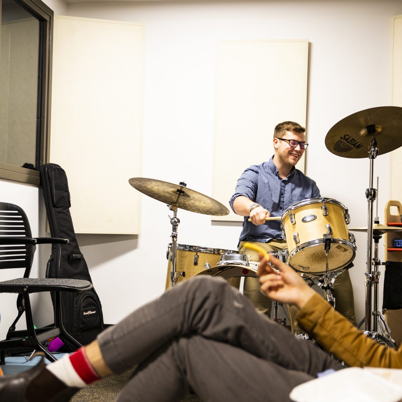 Group of students in a room playing drums and sitting on couches