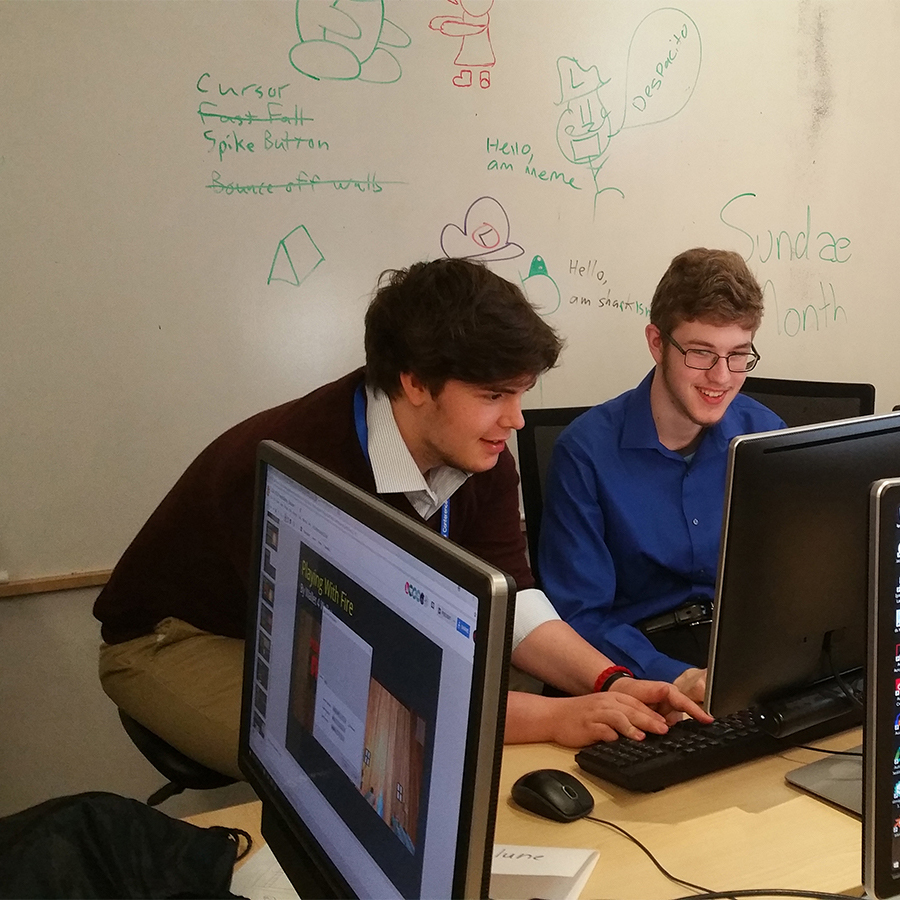 Two students smiling and working on a computer together